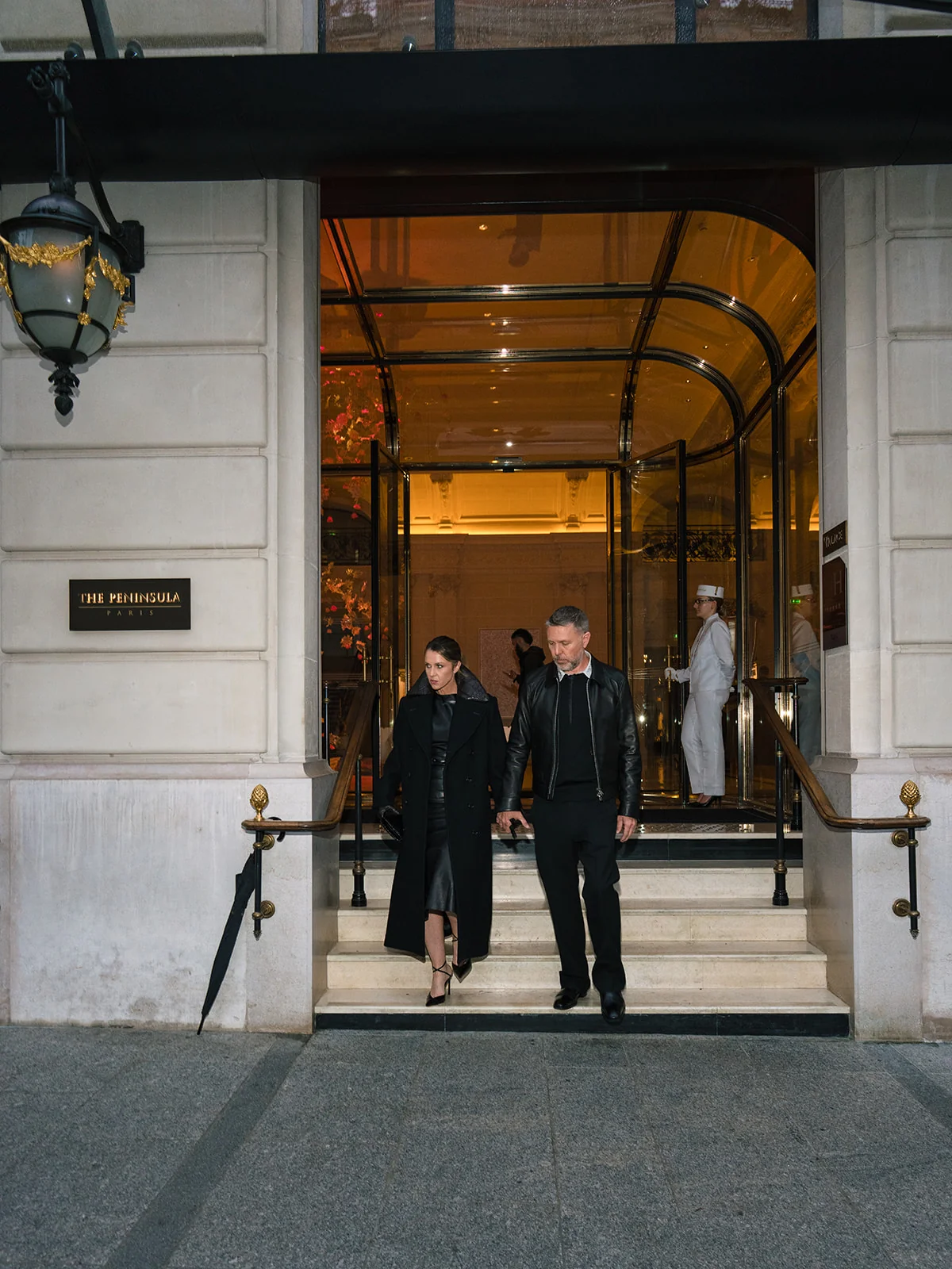 Deux personnes en tenues noires descendant les marches du Peninsula Paris