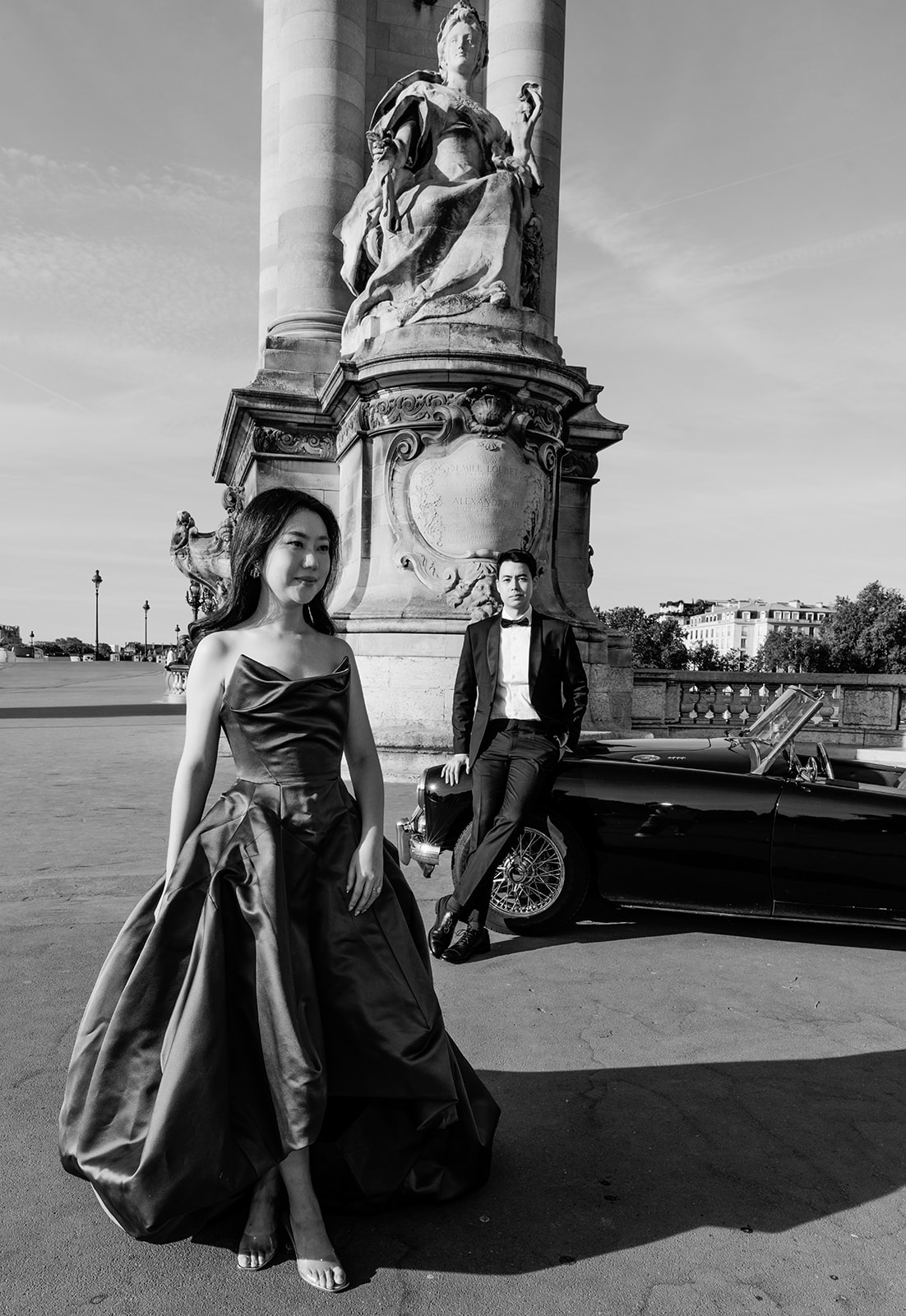 Black and white pre-wedding couple with a vintage MG roadster near Pont Alexandre III in Paris