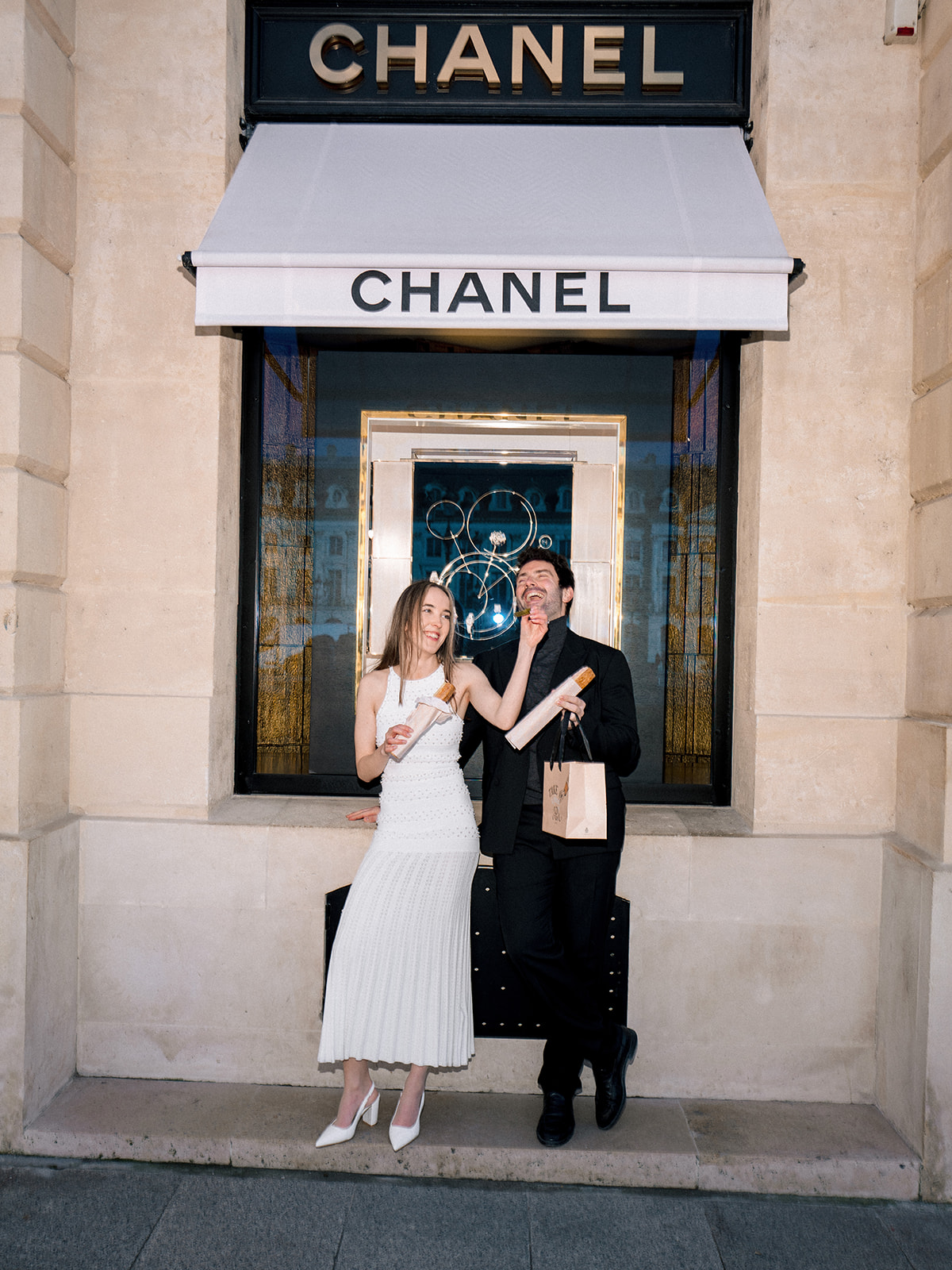 Playful editorial couple portrait with Paris pastries outside Chanel on Rue Cambon