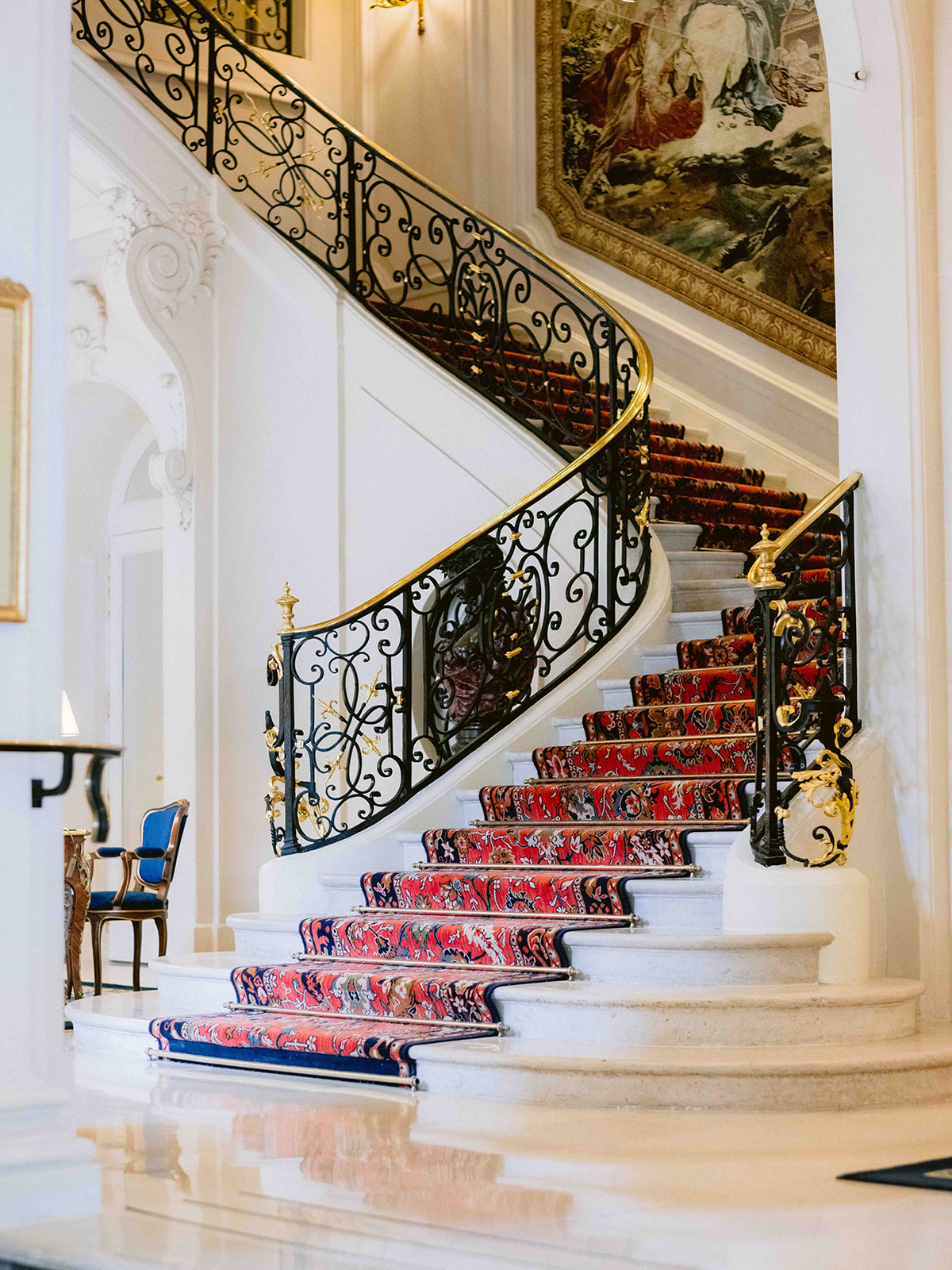 Grand escalier historique du Ritz Paris avec rampe en fer forgé et tapis rouge