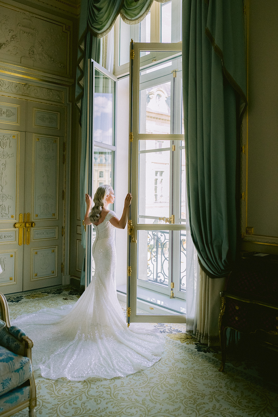 Mariée ouvrant les fenêtres de sa suite avant son mariage à Paris