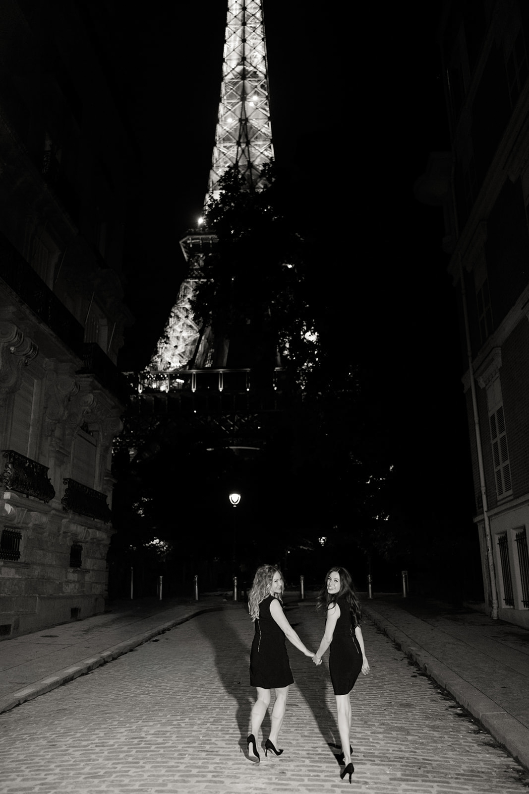 Couple walking hand in hand beneath the Eiffel Tower at night