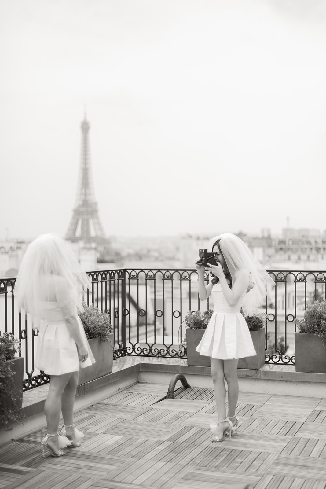 Couple photographing each other on a Peninsula Paris terrace with the Eiffel Tower behind them