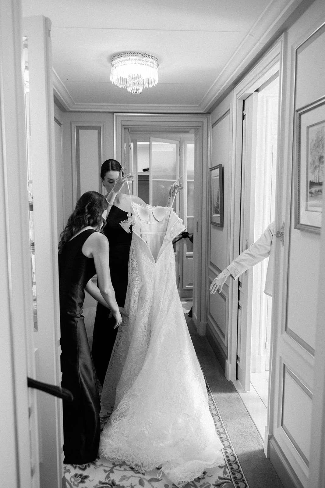 Bridesmaids arranging a lace wedding gown in a luxury Paris suite