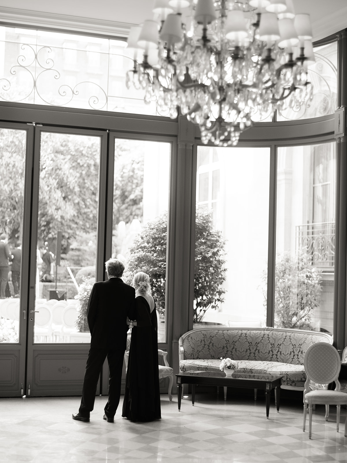 Parents watching the wedding ceremony through the windows of a Paris salon