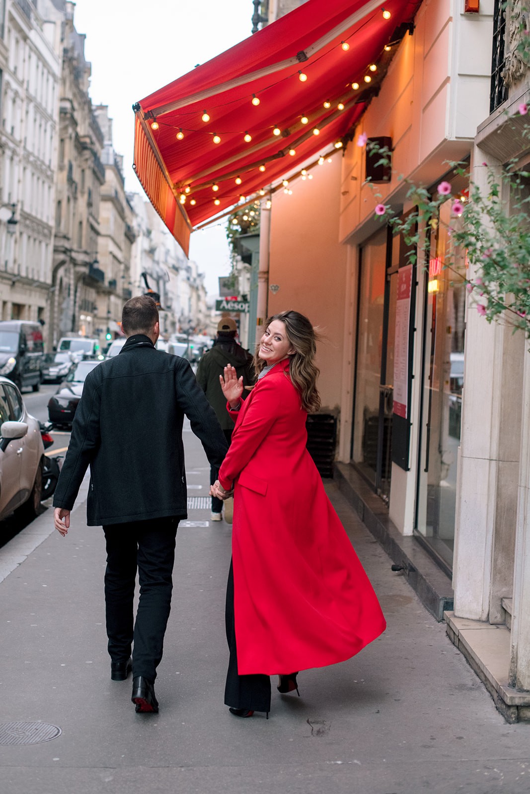 Couple walking through Paris during a pre-wedding session with a red statement coat