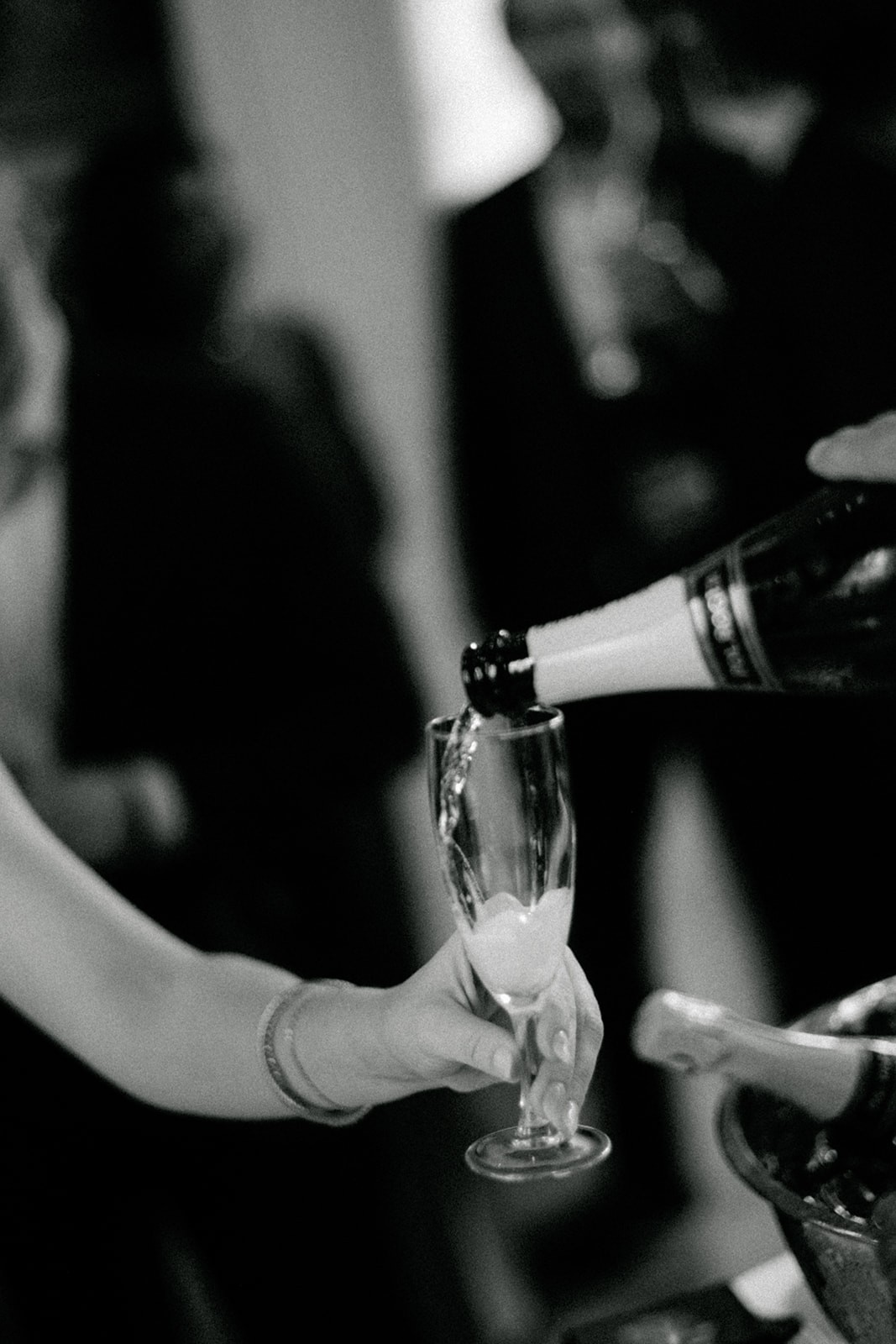 Black-and-white detail of champagne being served during a Paris wedding welcome dinner