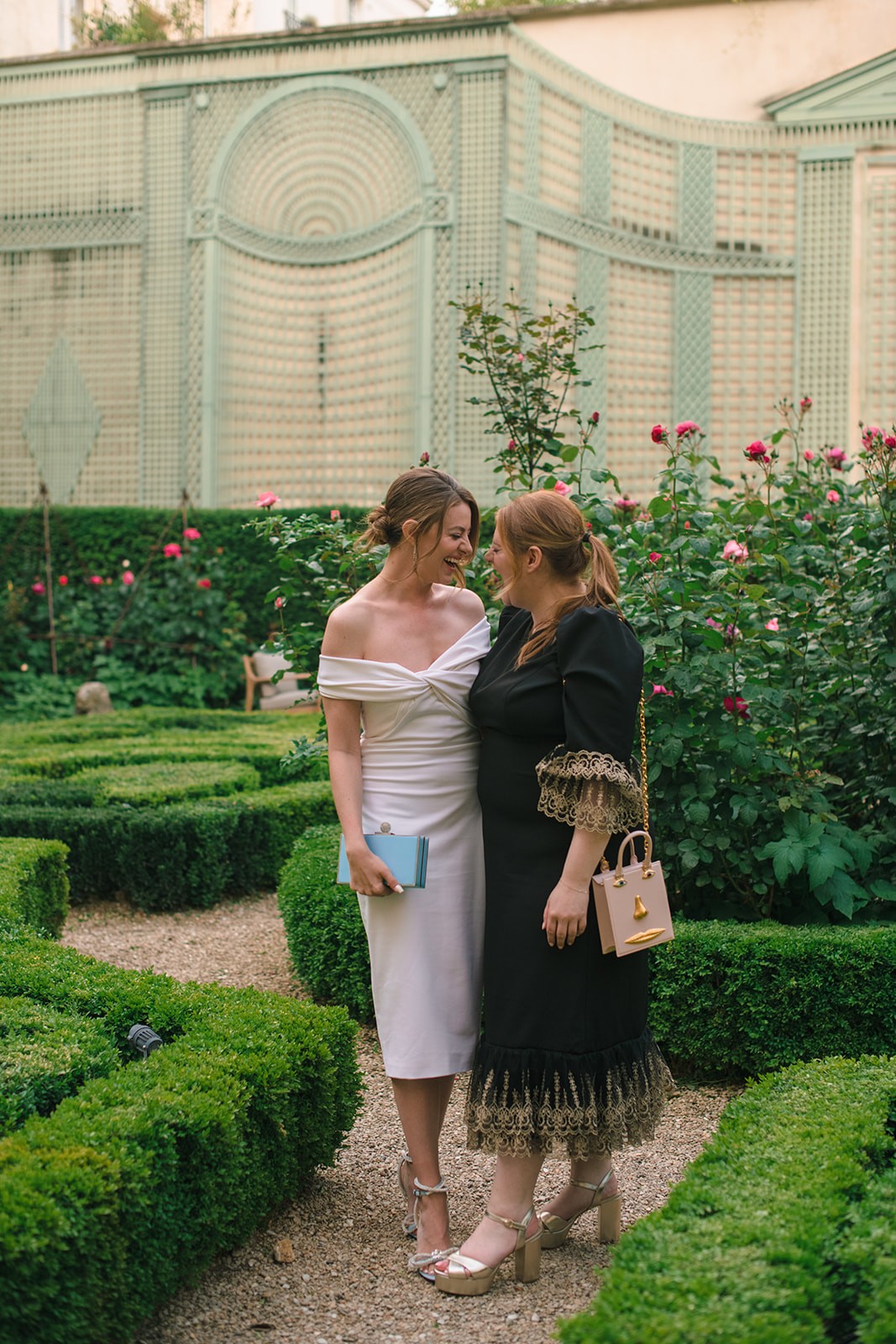 Bride-to-be sharing a candid moment with a guest in the garden at the Paris welcome dinner