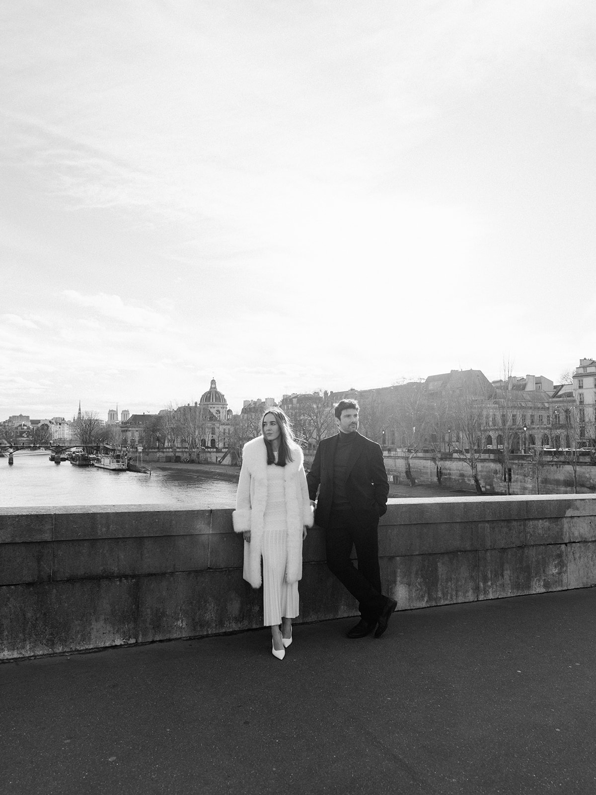 Wide black-and-white editorial portrait of a couple overlooking the Seine in Paris