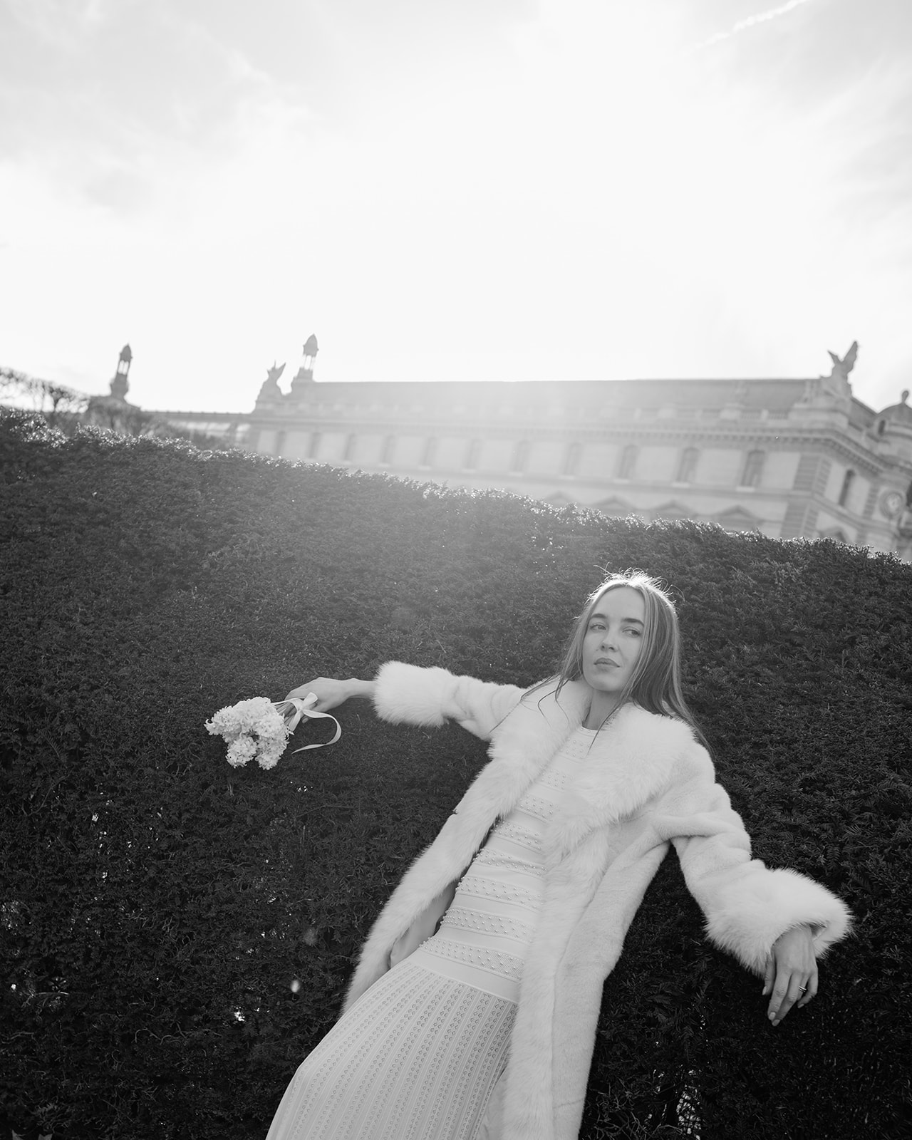 Black-and-white editorial portrait in a white fur coat in the Tuileries Garden
