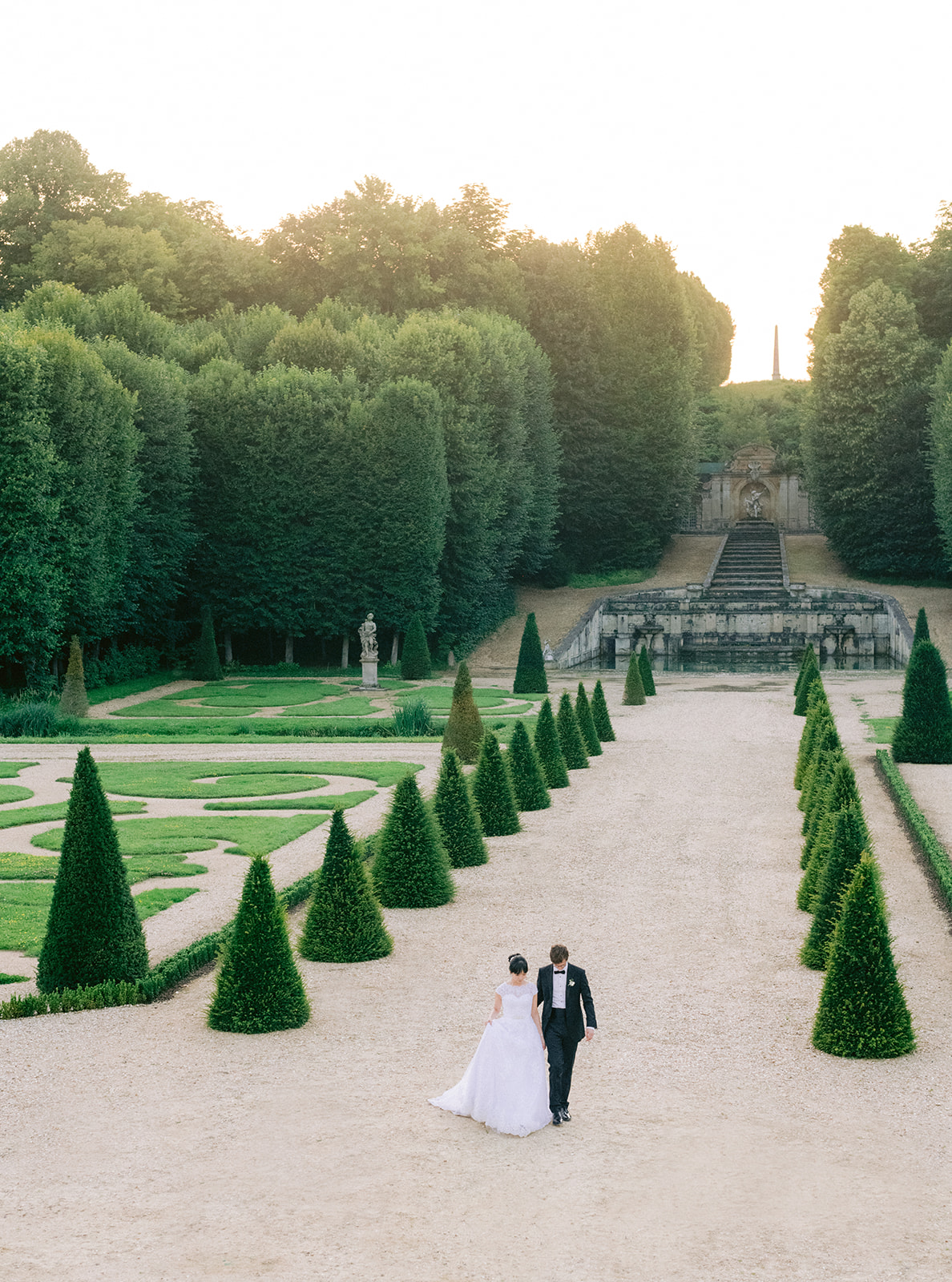 Wedding couple walking through the formal gardens of Château de Villette near Paris