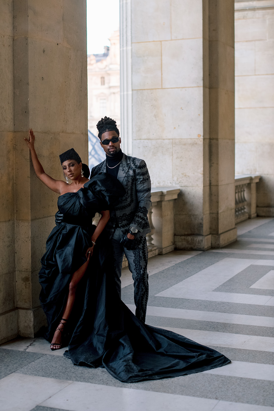 Candice Craig and Omar Bolden posing together beside a stone column at the Louvre