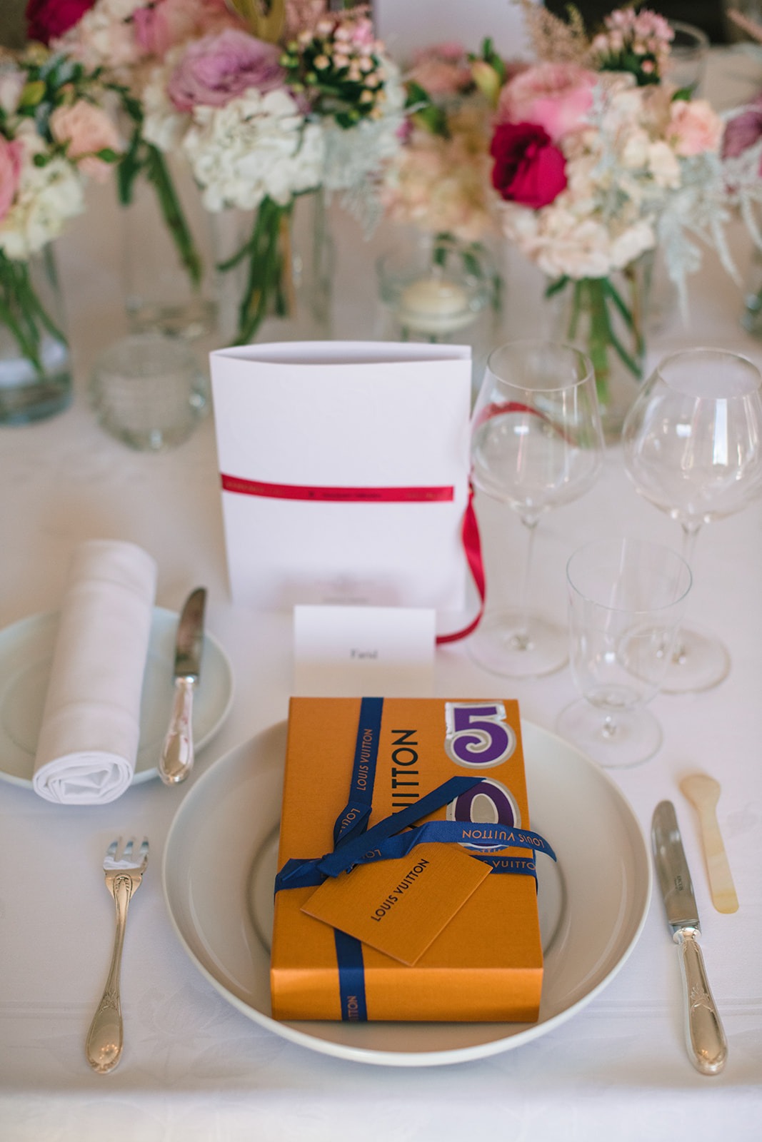 Louis Vuitton birthday gift arranged at a place setting with pink florals inside Hôtel Plaza Athénée Paris