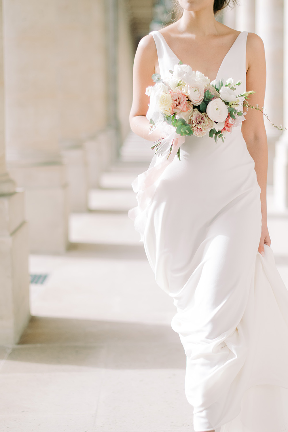 Une mariée marche avec une robe très élégante et un bouquet à lamain