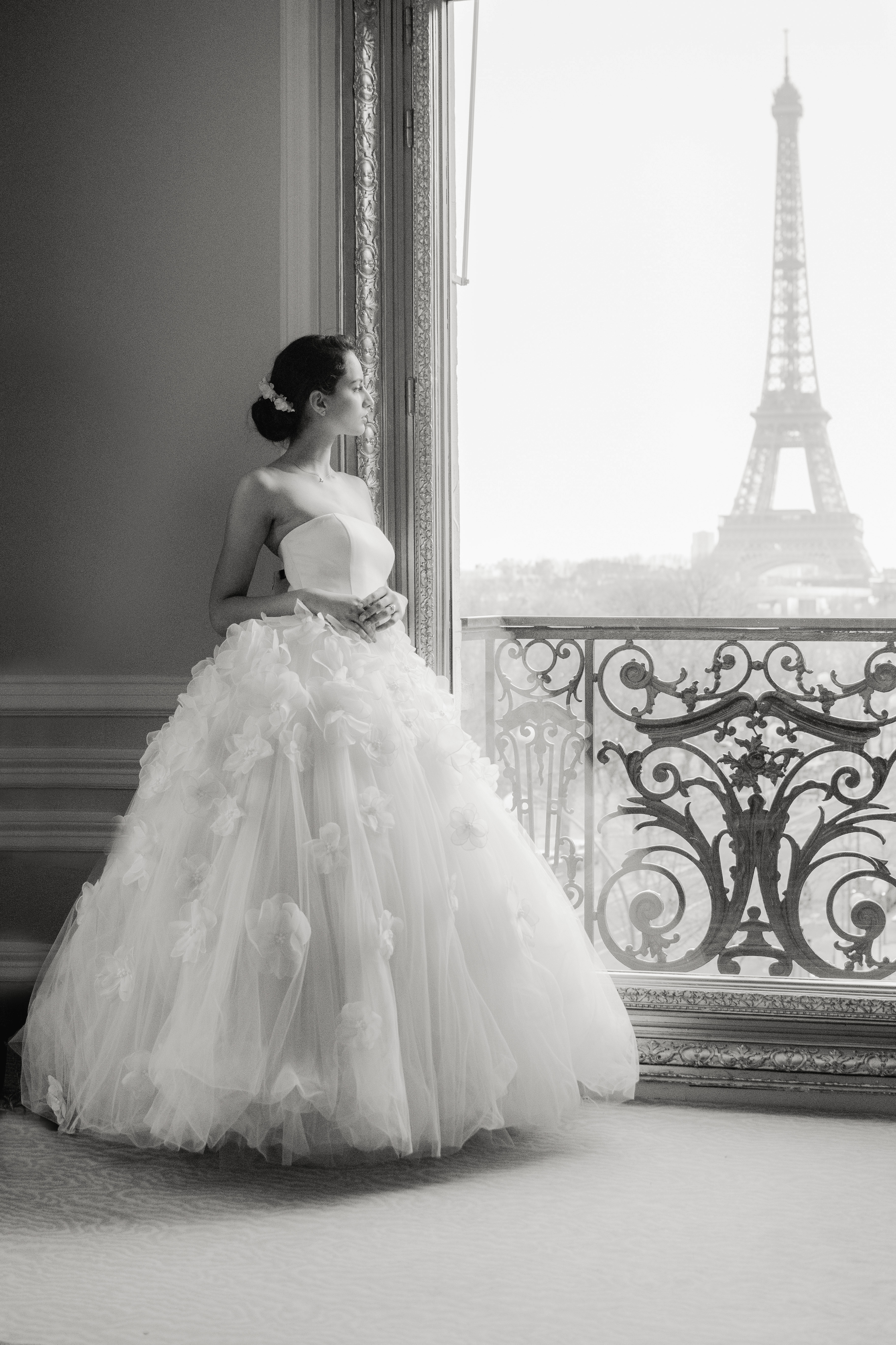 une mariée regarde la tour effeil par la fenetre de la suite du plaza athénée