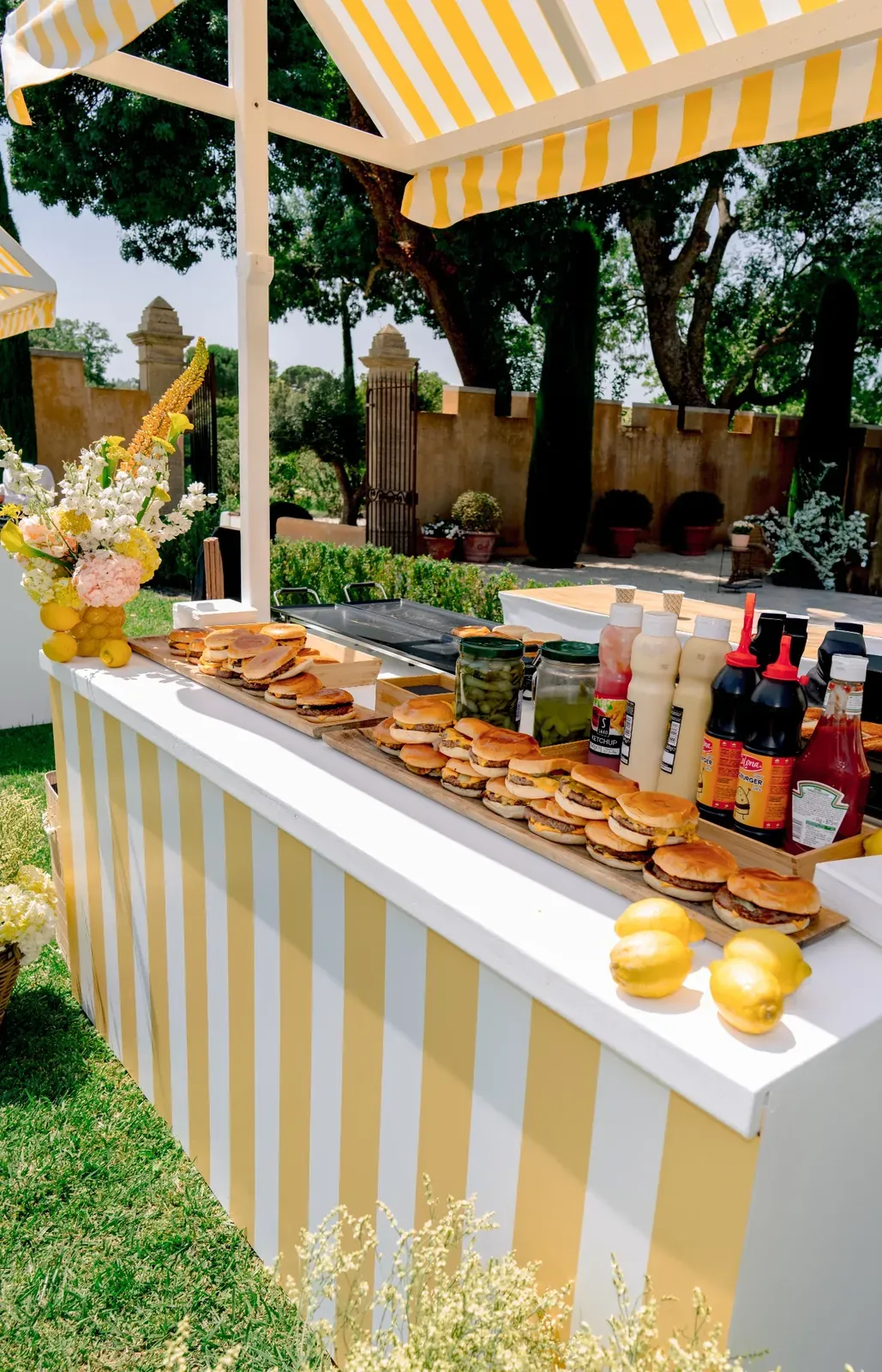 Burger bar with yellow striped awning during the Day 1 pool party at Villa Baulieu in Provence