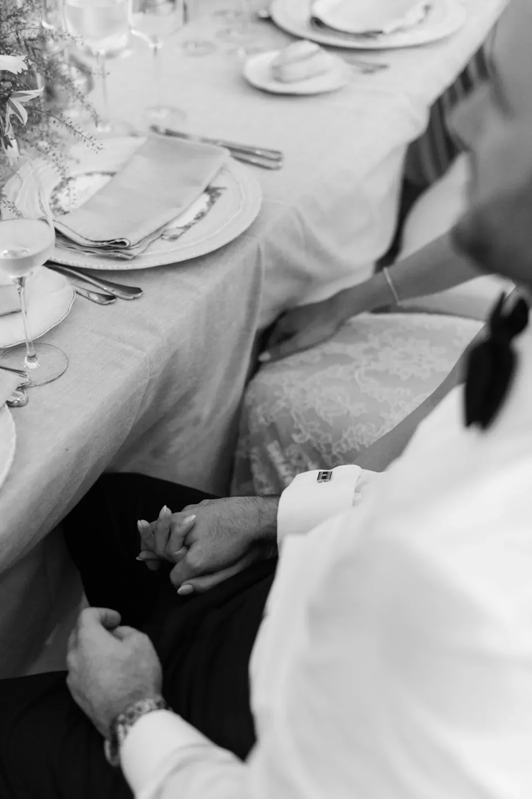 Black and white candid of guests holding hands during the Villa Baulieu wedding dinner