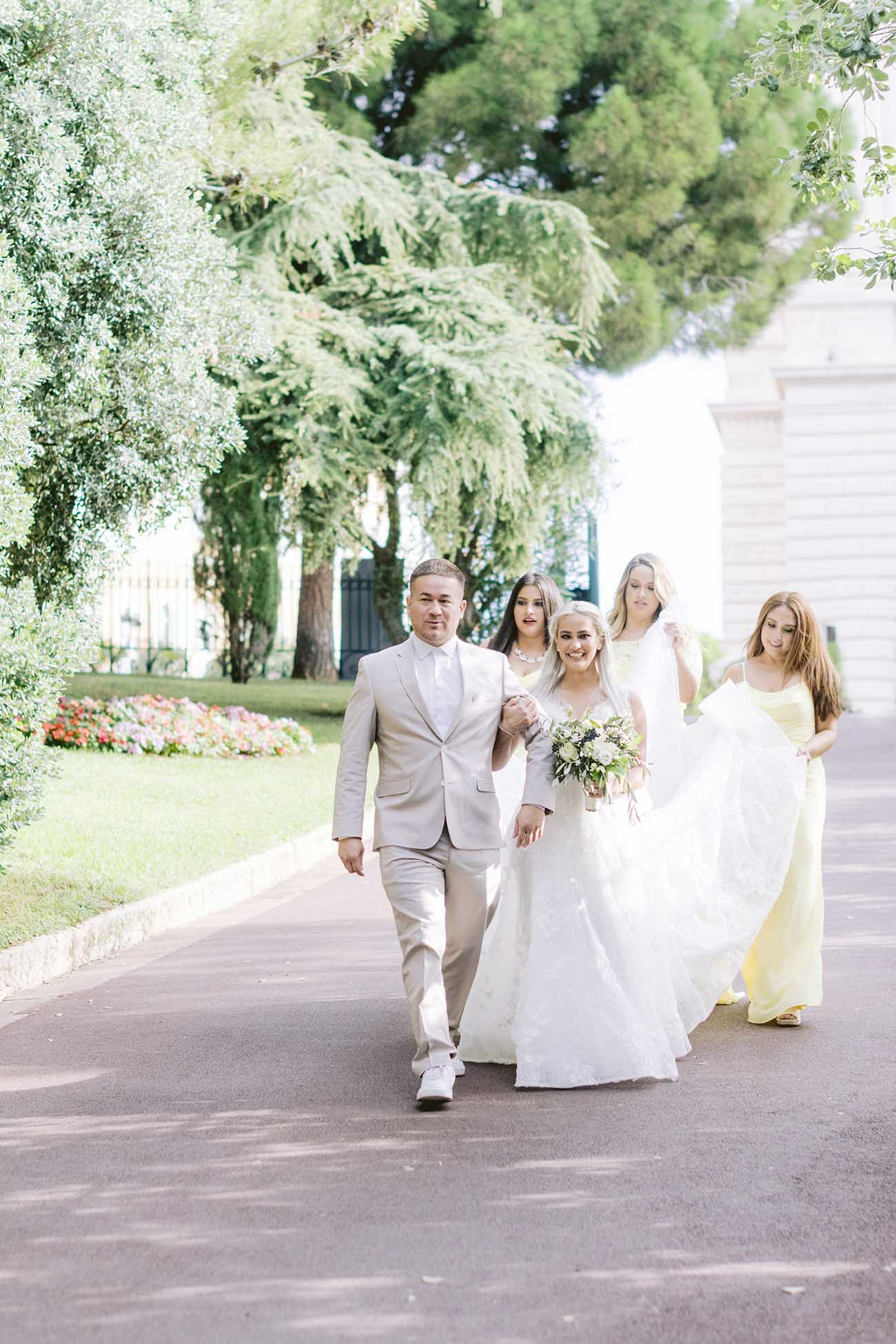 la mariée est sous son voile avec un bouquet de fleurs à la main