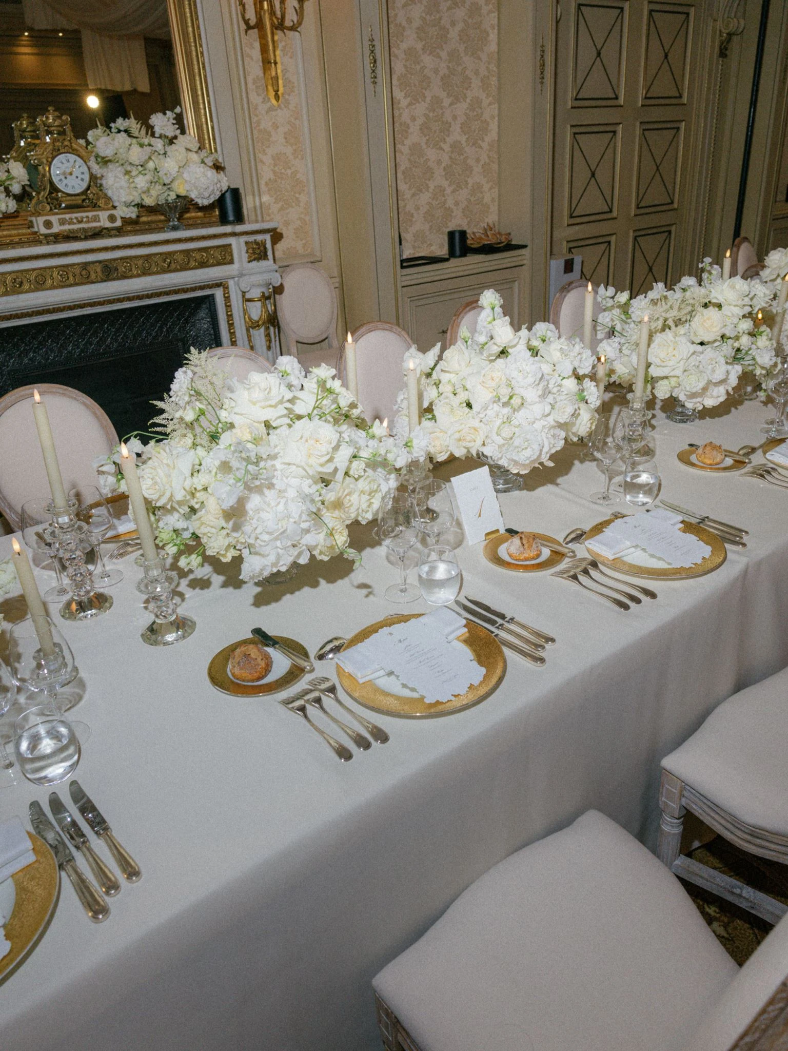 Wedding reception table with white flowers, candles and gold-rimmed plates at Shangri-La Paris